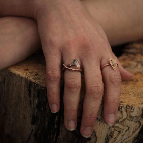 Ginkgo leaf ring and bronze leaf ring on hand posed on log