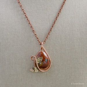 pendant with red stone set in copper with a twisting vine