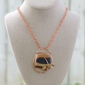 mutli colored petrified wood stone set in copper setting with twisting vine and copper chain